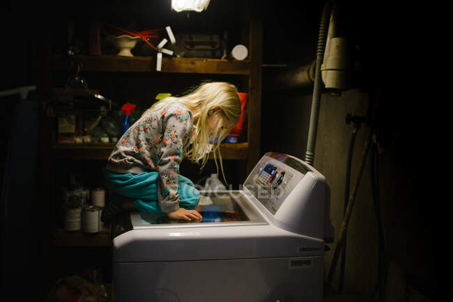 Petite fille assise sur la machine à laver — Photo de stock