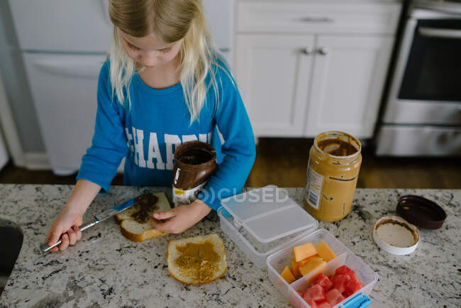 Маленькая девочка делает сэндвич на кухне — стоковое фото