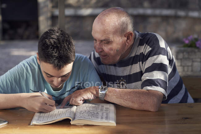Menino e seu avô fazendo palavras cruzadas — Fotografia de Stock