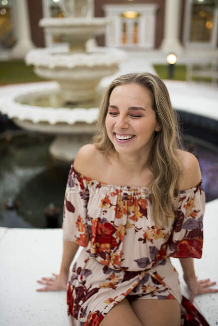 College student laughing by a fountain in a courtyard — Stock Photo