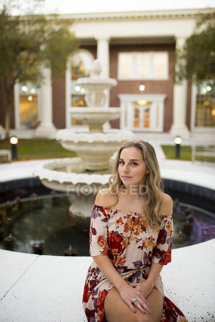 Дівчинка з коледжу, що стоїть біля фонтану в кампусі. — стокове фото