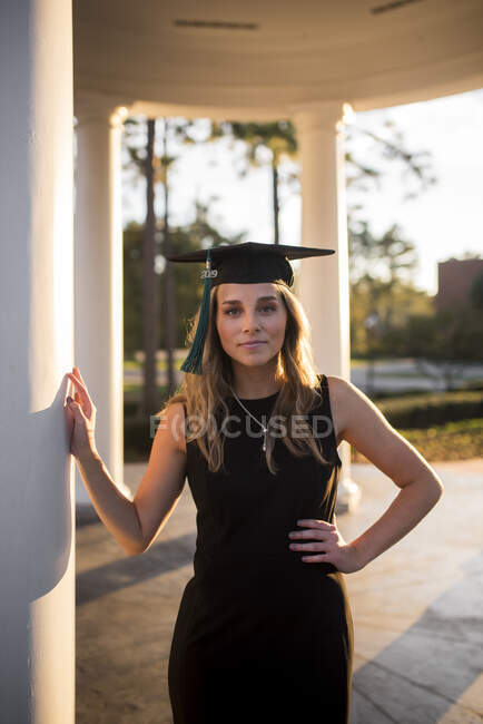 Estudante universitário posando no pátio com tampa de formatura — Fotografia de Stock