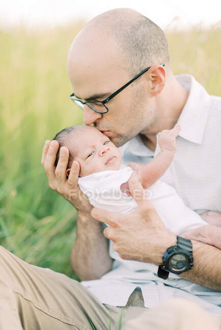 Отец нежно обнимает и целует своего новорожденного сына — стоковое фото