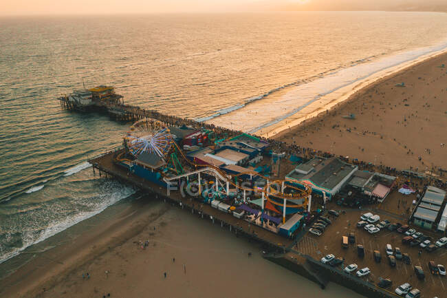 Circa November 2019: Santa Monica Pier, Los Angeles from above at beautiful Golden Hour Sunset in Orange light and Ferrys Wheel with ocean view and waves crashing HQ — Stock Photo
