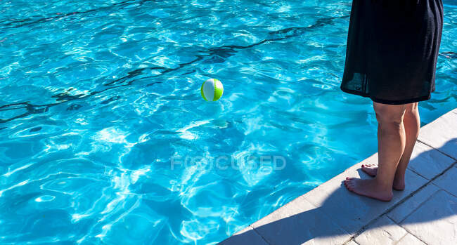Partial view of a woman's legs standing by the edge of a swimming pool — Stock Photo
