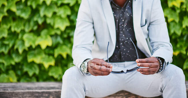 African American man sitting on a park bench. He is a handsome businessman. — Stock Photo