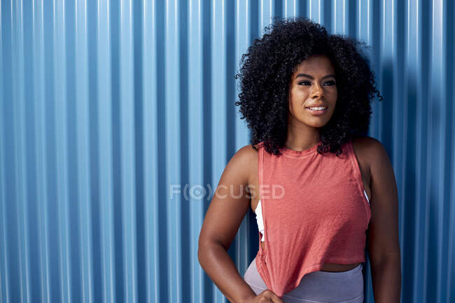 Young woman in athleisure clothing against a blue background — Stock Photo