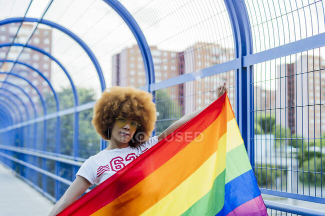 Гордая женщина со своим флагом гей-гордости на мосту — стоковое фото