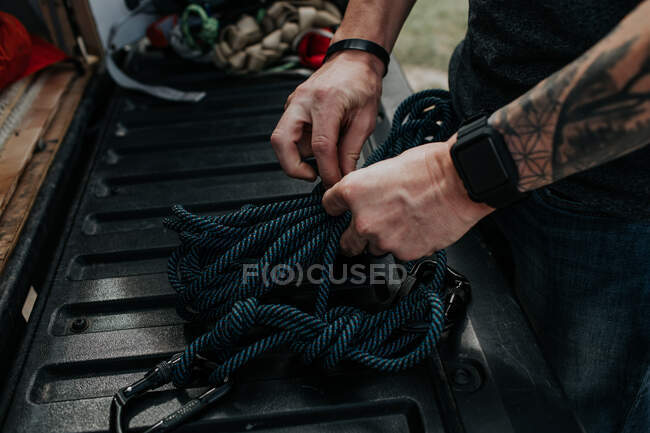 Чоловік сидить на спині вантажівки готує скелелазіння мотузки — стокове фото