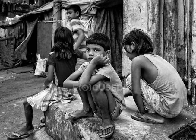 Um garoto perdido em pensamento enquanto sentado em uma esquina de rua — Fotografia de Stock