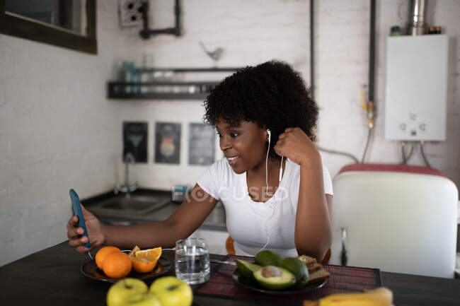 Glad black lady calling to friends through video chat app during healthy breakfast — Stock Photo