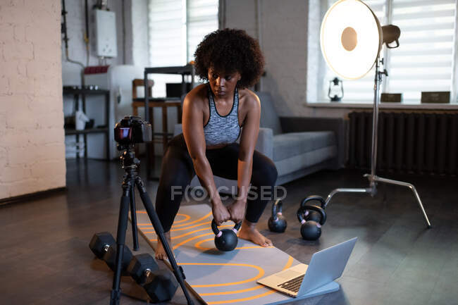 Forte allenatore nero che fa esercizio di peso vicino alla fotocamera durante l'allenamento online a casa — Foto stock