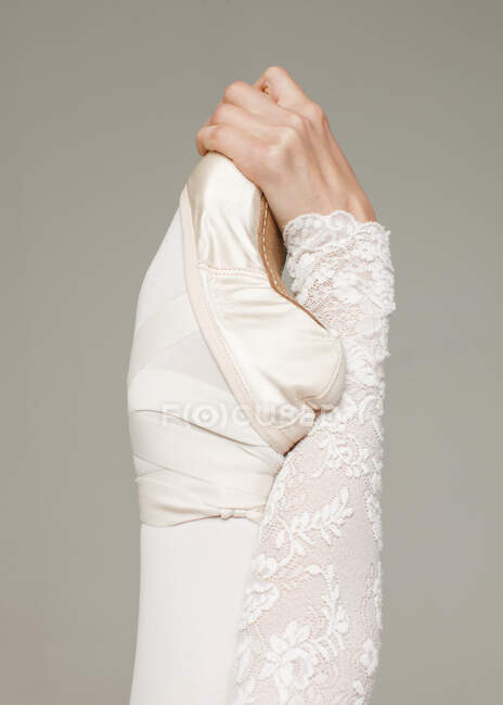 Weibliche Hand hält Füße in Ballettschuhzehe isoliert auf grauem Hintergrund, Nahaufnahme Detailaufnahme — Stockfoto