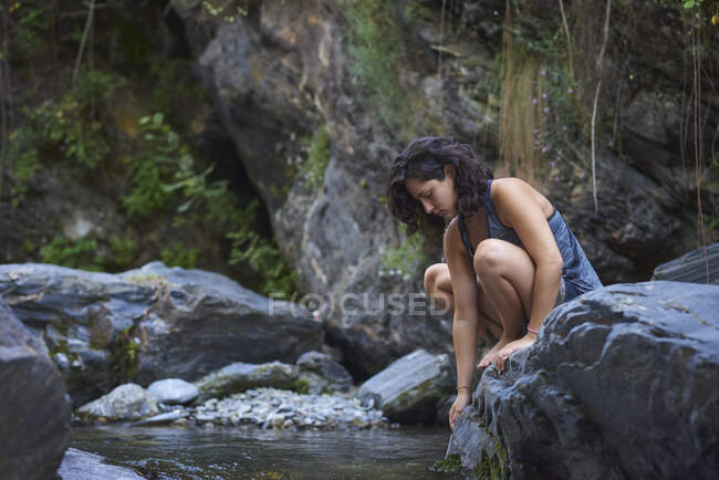Una joven en un río. Refresca en una cálida tarde de verano. - foto de stock