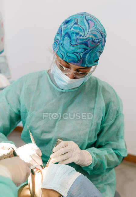 Asistente de dentista inserta herramienta en la boca del paciente - foto de stock