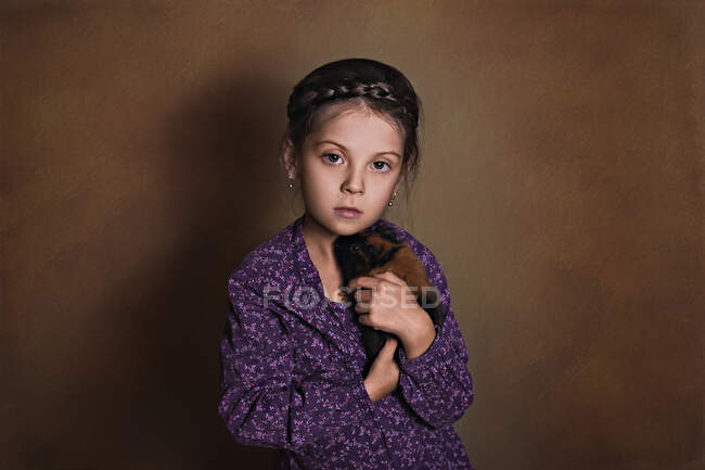 Bella bambina che tiene un porcellino d'India su uno sfondo di carta marrone — Foto stock