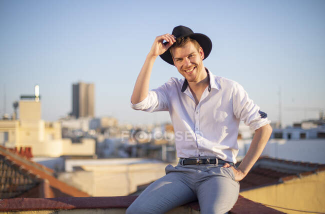 Rapaz sorridente com chapéu no telhado de um edifício — Fotografia de Stock