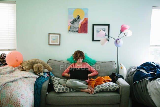 Adolescente chica en su portátil en su dormitorio desordenado - foto de stock