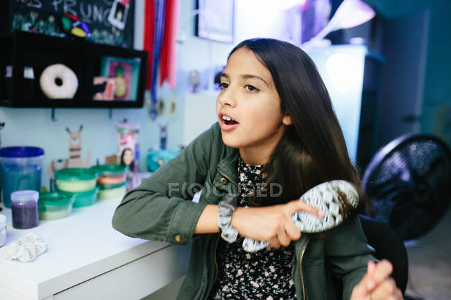 Entre fille brossant ses cheveux dans sa chambre — Photo de stock