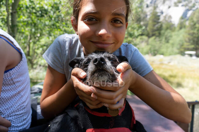 Tween Girl segura o rosto do cão e sorri para a câmera — Fotografia de Stock