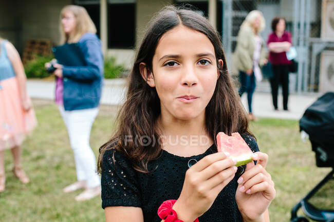 Menina olha para a câmera depois de dar uma mordida de melancia — Fotografia de Stock