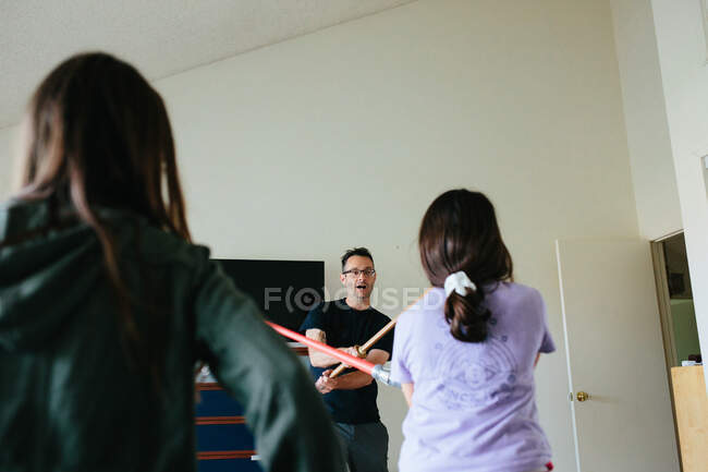 Man has a sword fight with toy sword and light saber with girls — Stock Photo