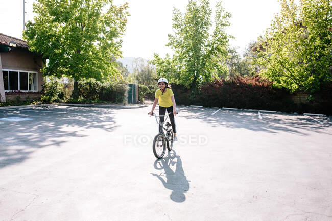 Tween girl stands on the pedals of her bike while smiling — Stock Photo