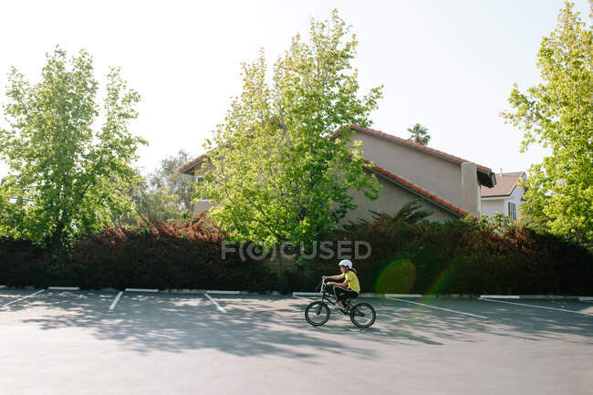 Perfil de tiro largo da menina andando de bicicleta em um estacionamento — Fotografia de Stock