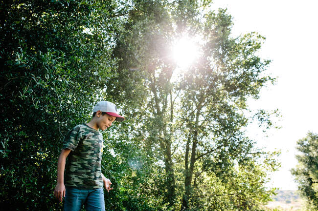 Perfil de um menino vestindo uma camisa de camuflagem enquanto fora na natureza — Fotografia de Stock