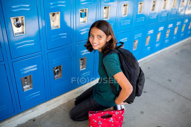 Tween girl smiles in front of her locker at middle school — Stock Photo