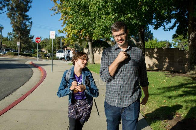 Daughter looks up at father as he walks with her to school — Stock Photo