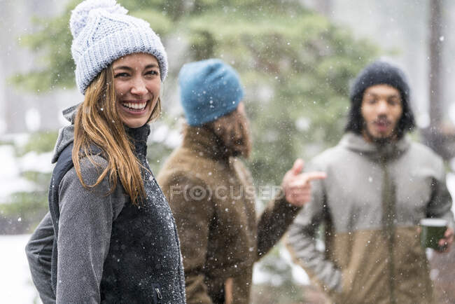 Mujer joven pasando el rato con amigos en el bosque en invierno - foto de stock