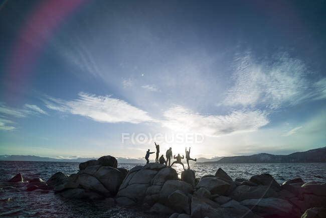 Silhouette di gruppo di amici che fanno pose stupide sulla spiaggia — Foto stock
