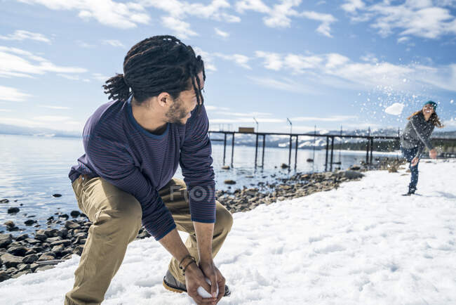 A man and woman have a snowball fight near a pier in South Lake Tahoe, CA — Stock Photo