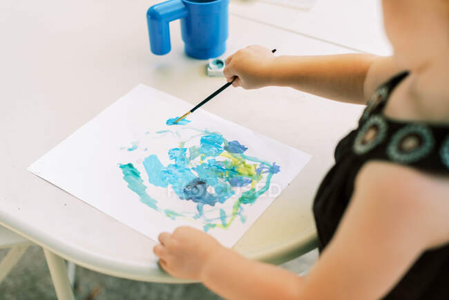 Toddler painting with watercolors outside on the patio — Stock Photo