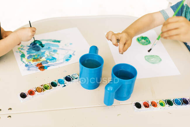 Little artists painting with watercolors outside on the patio — Stock Photo