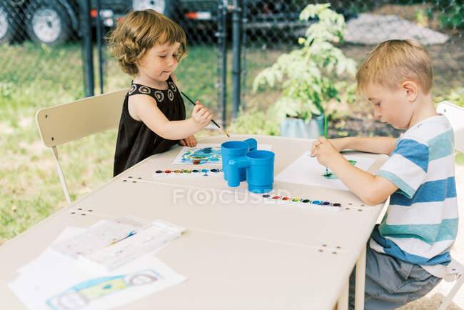 Pequeños artistas pintando con acuarelas en el patio - foto de stock