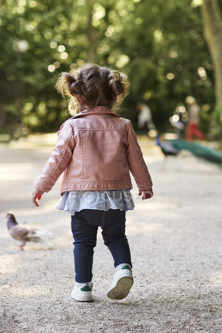 Una ragazza di 18 mesi che insegue un piccione in un parco — Foto stock