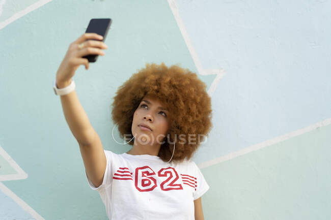 Mujer con cabello afro tomando una selfie con su smartphone - foto de stock