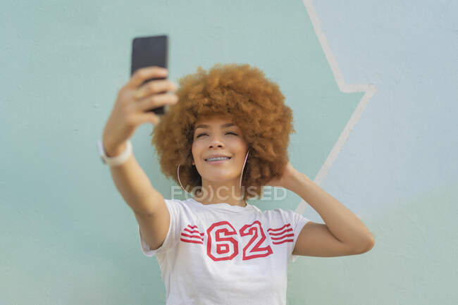 Mulher com cabelo afro tomando uma selfie — Fotografia de Stock