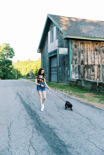 A teenage girl walking her puppy on a leash in a field — Stock Photo