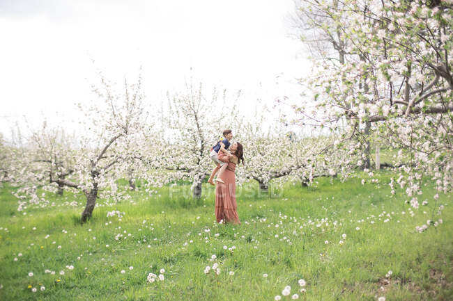 Retrato de una madre con su hijo en un huerto de manzanas - foto de stock