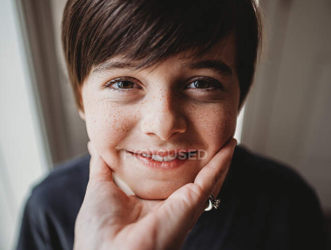Крупним планом обличчя щасливого хлопчика тримається під підборіддям за руку . — стокове фото