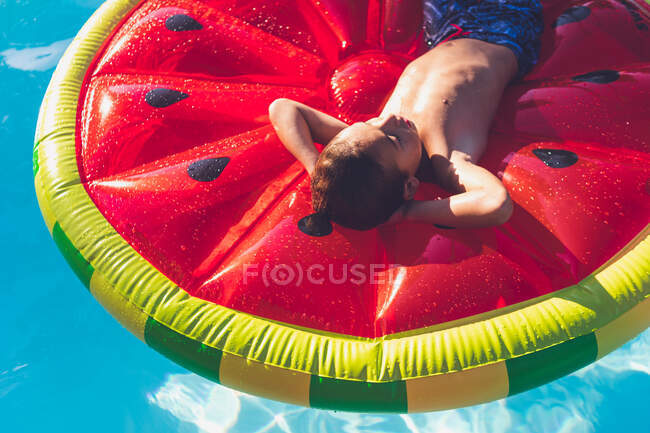 Boy chilling in pool on watermelon float — Stock Photo