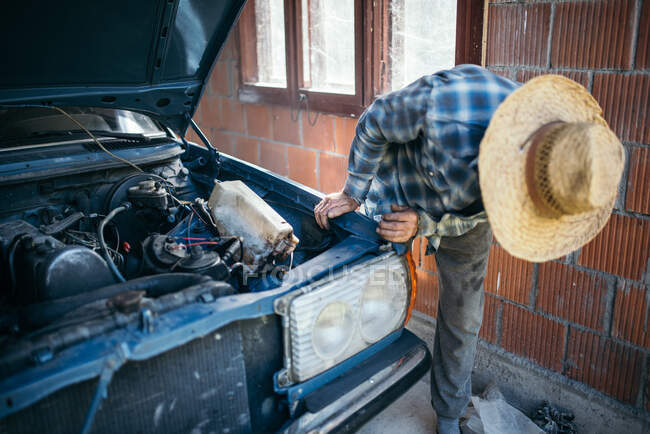 Velho trabalhando em carro vintage em sua garagem em casa — Fotografia de Stock