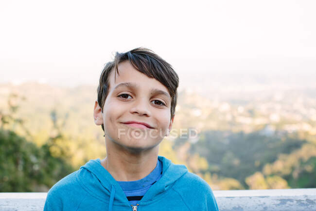 Sorrindo areias menino de dez anos de idade na frente de uma vista vista sobre LA — Fotografia de Stock