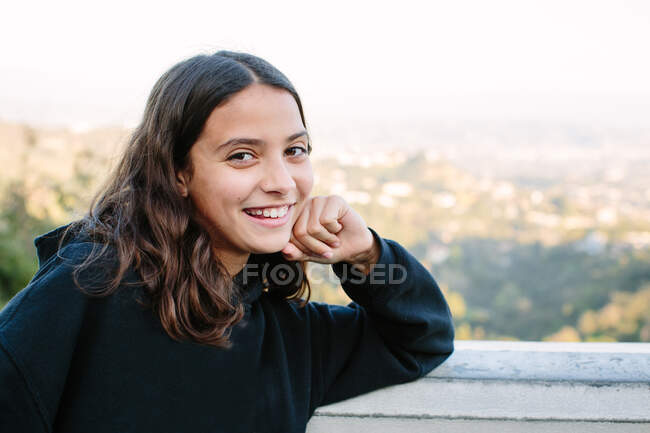 Douze ans fille sourit pour un portrait fromager à un panorama surplombant — Photo de stock