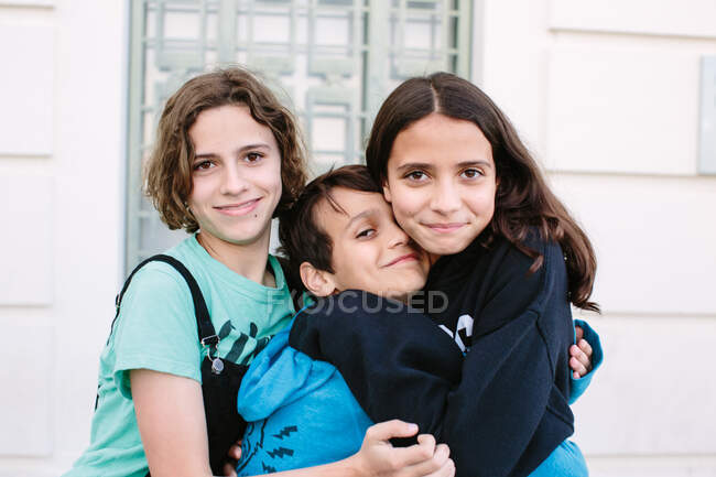 Young teen girls make a brother sandwich as they embrace — Stock Photo