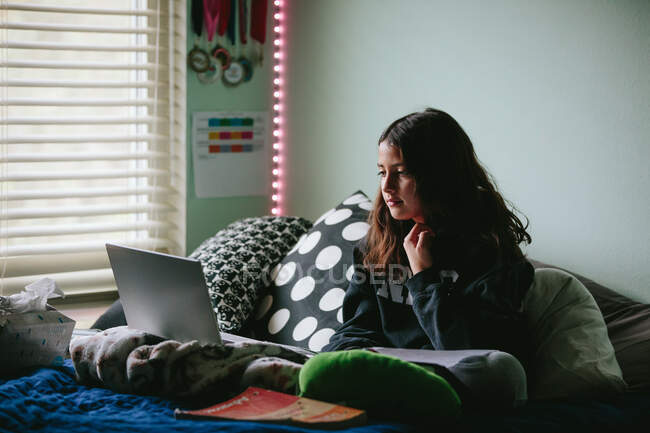 Tra ragazza guardando il suo schermo del computer portatile durante una riunione di classe di zoom — Foto stock