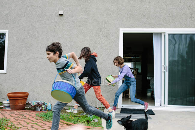 I fratelli si precipitano fuori con i loro cestini pasquali vuoti per raccogliere le uova. — Foto stock